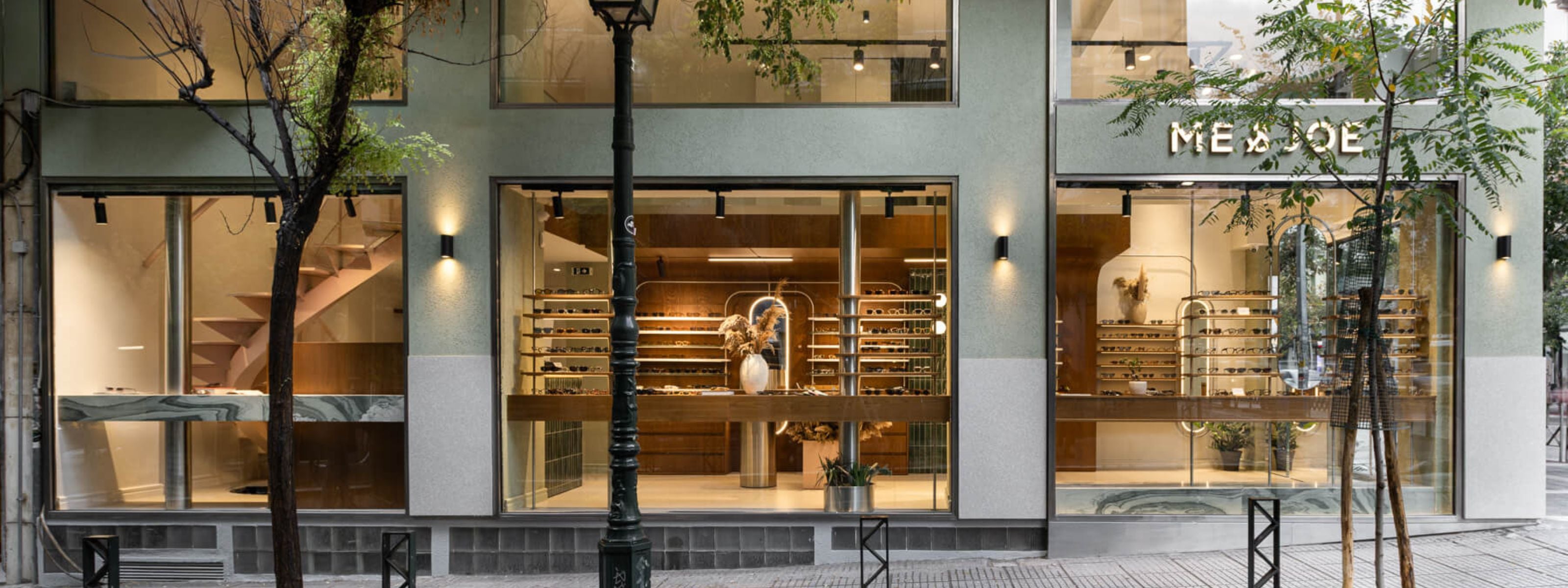 Panoramic street view of the ME & JOE Tsimiski store exterior with large glass windows showcasing the eyewear displays inside.