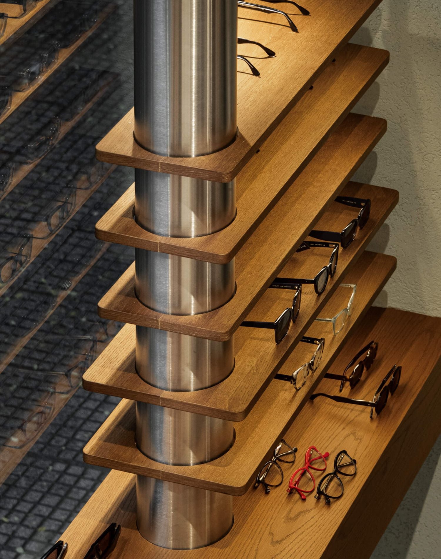 Interior view of the ME & JOE Tsimiski store featuring wall displays, sunglasses shelves, and inox design elements.