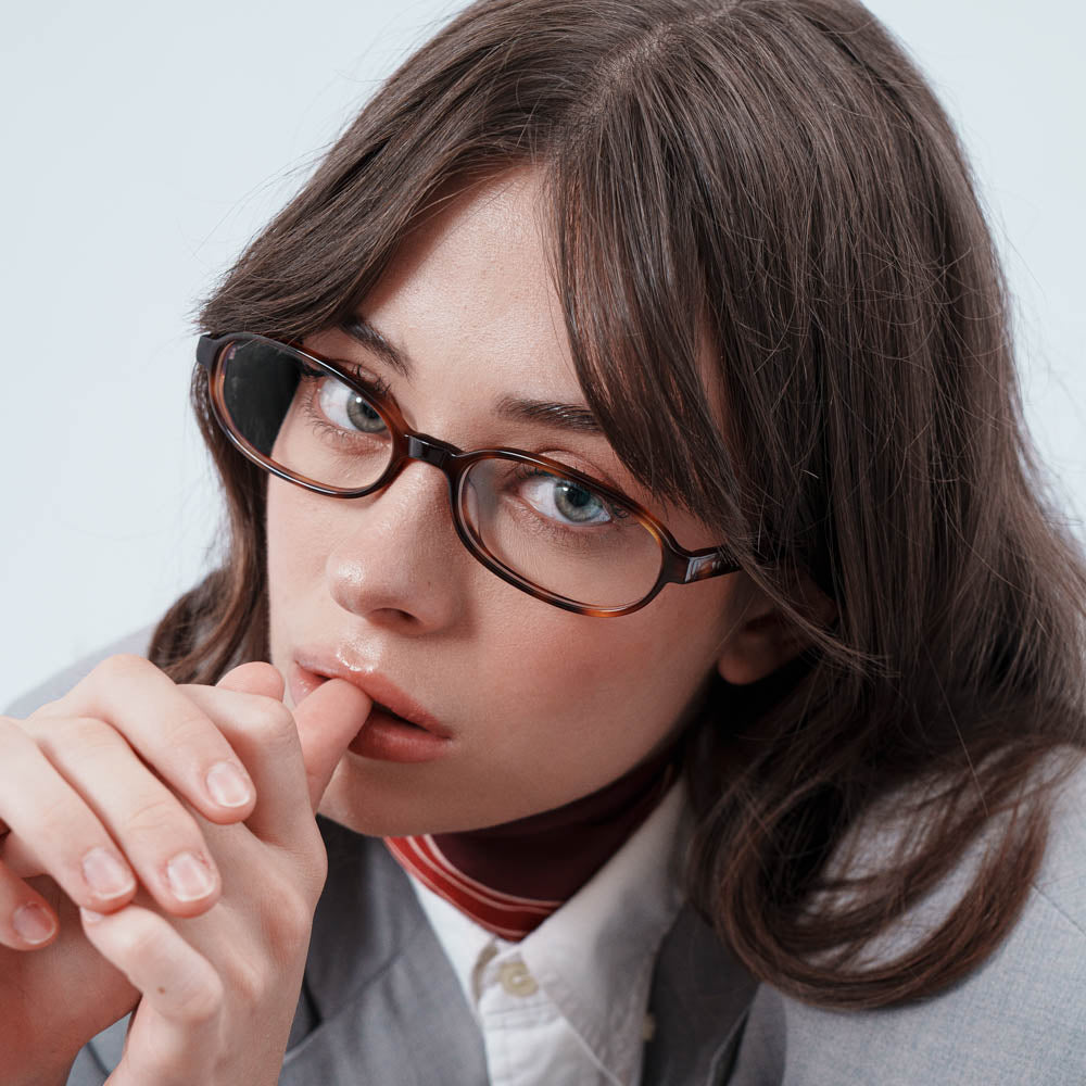 Woman wearing glasses and a gray suit with a white shirt.