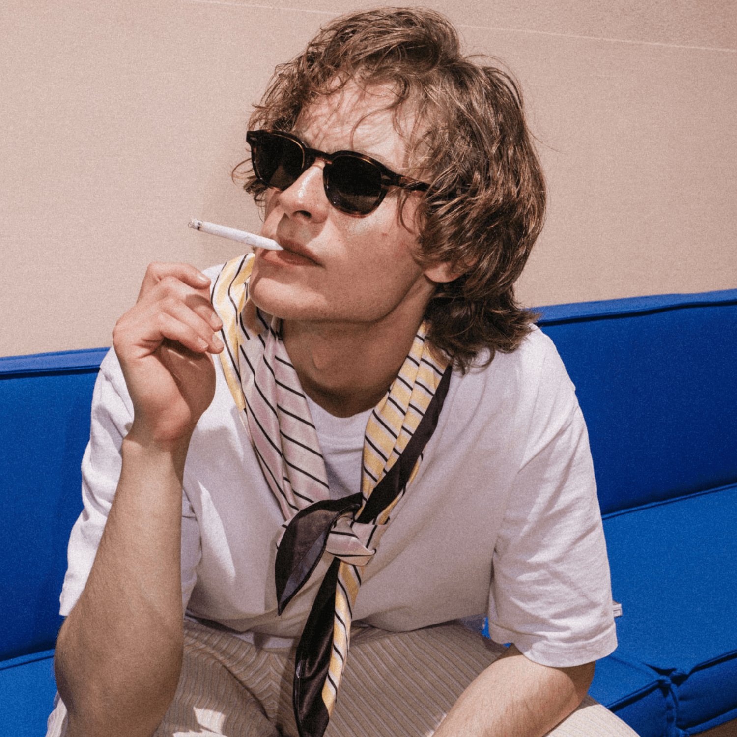 ME & JOE Taylor tortoise sunglasses worn by model sitting on a blue sofa