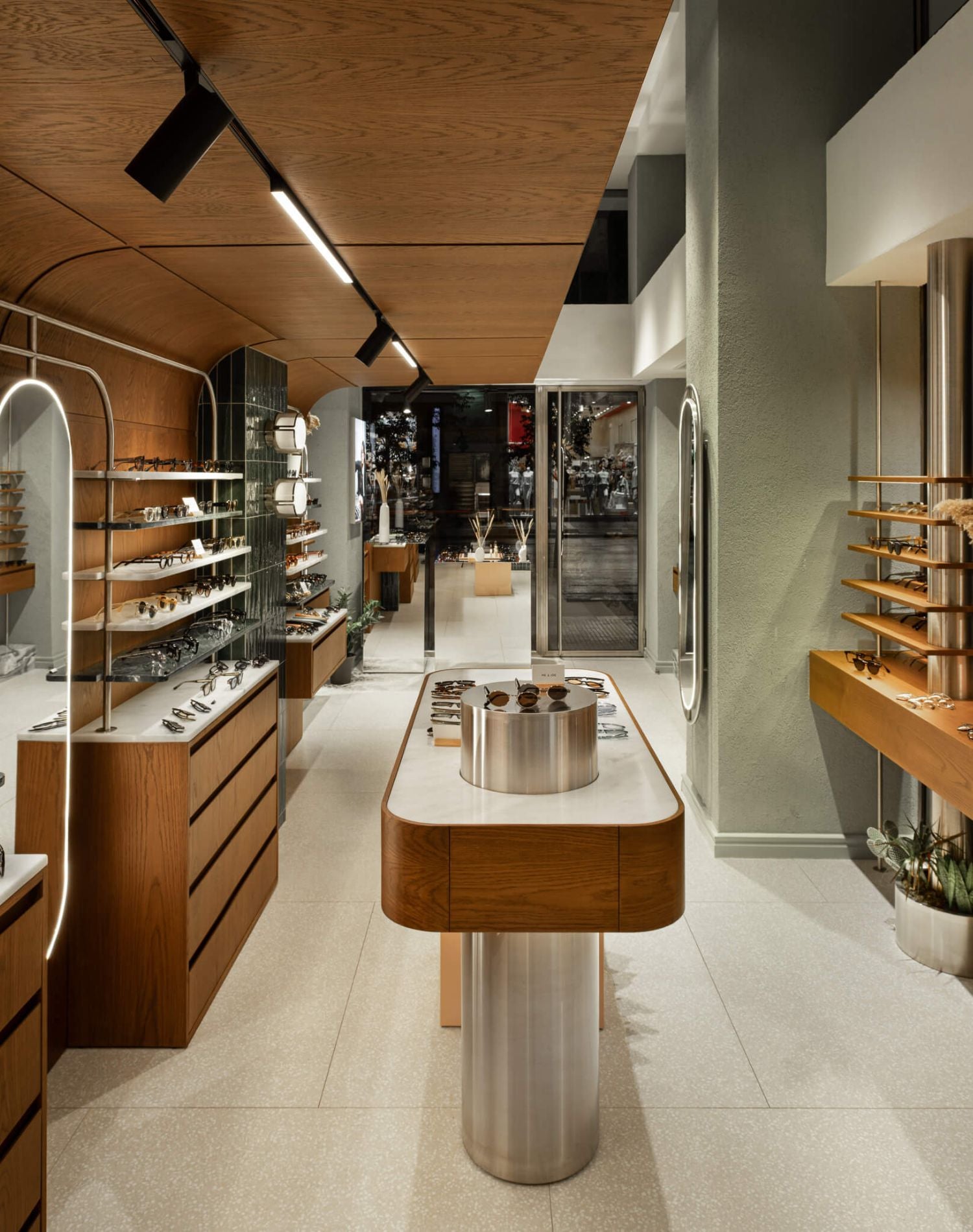 Interior view of the ME & JOE Tsimiski store featuring wall displays, sunglasses shelves, and oak-and-green design elements.