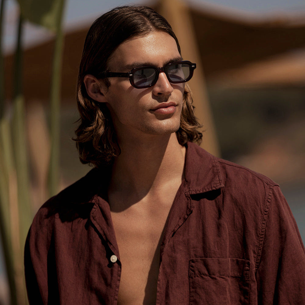 Man wearing sunglasses and a brown shirt in a desert setting